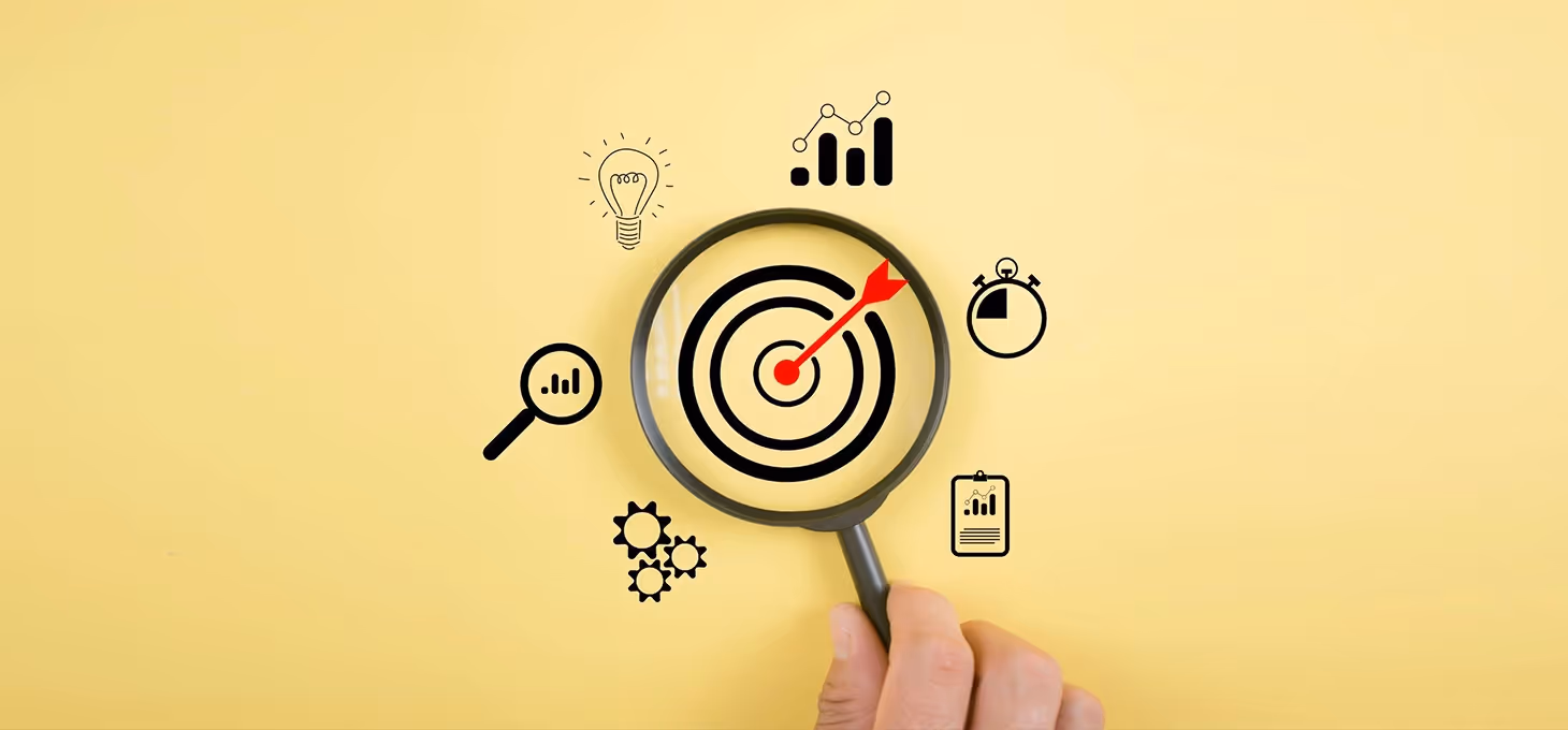 A magnifying lens rests on a yellow background, with an arrow hitting the target.