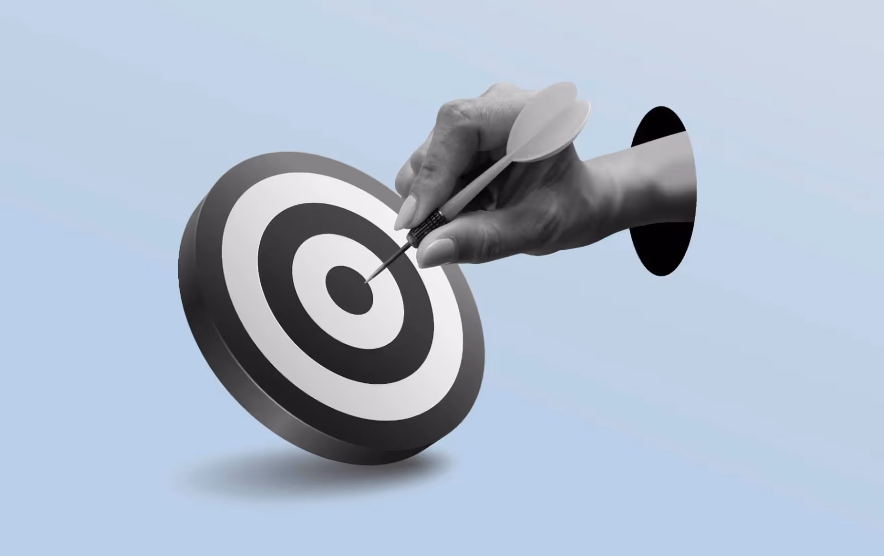 A black and white hand holds a dart, about to put it in the bullseye.