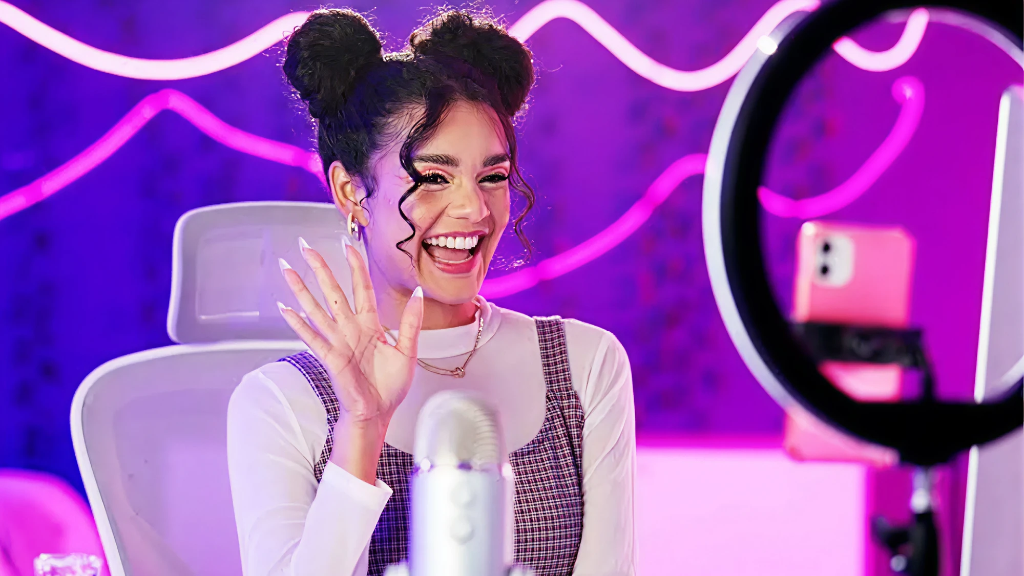 Smiling content creator filming herself with a ring light and microphone in a colorful studio