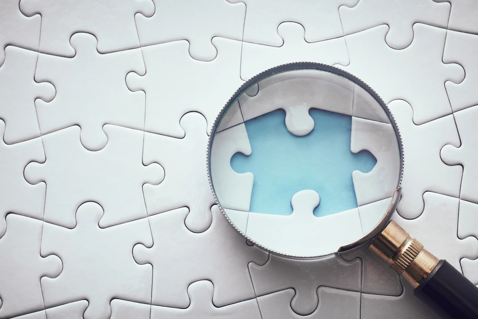 A magnifying glass focusing on the missing piece in an incomplete puzzle