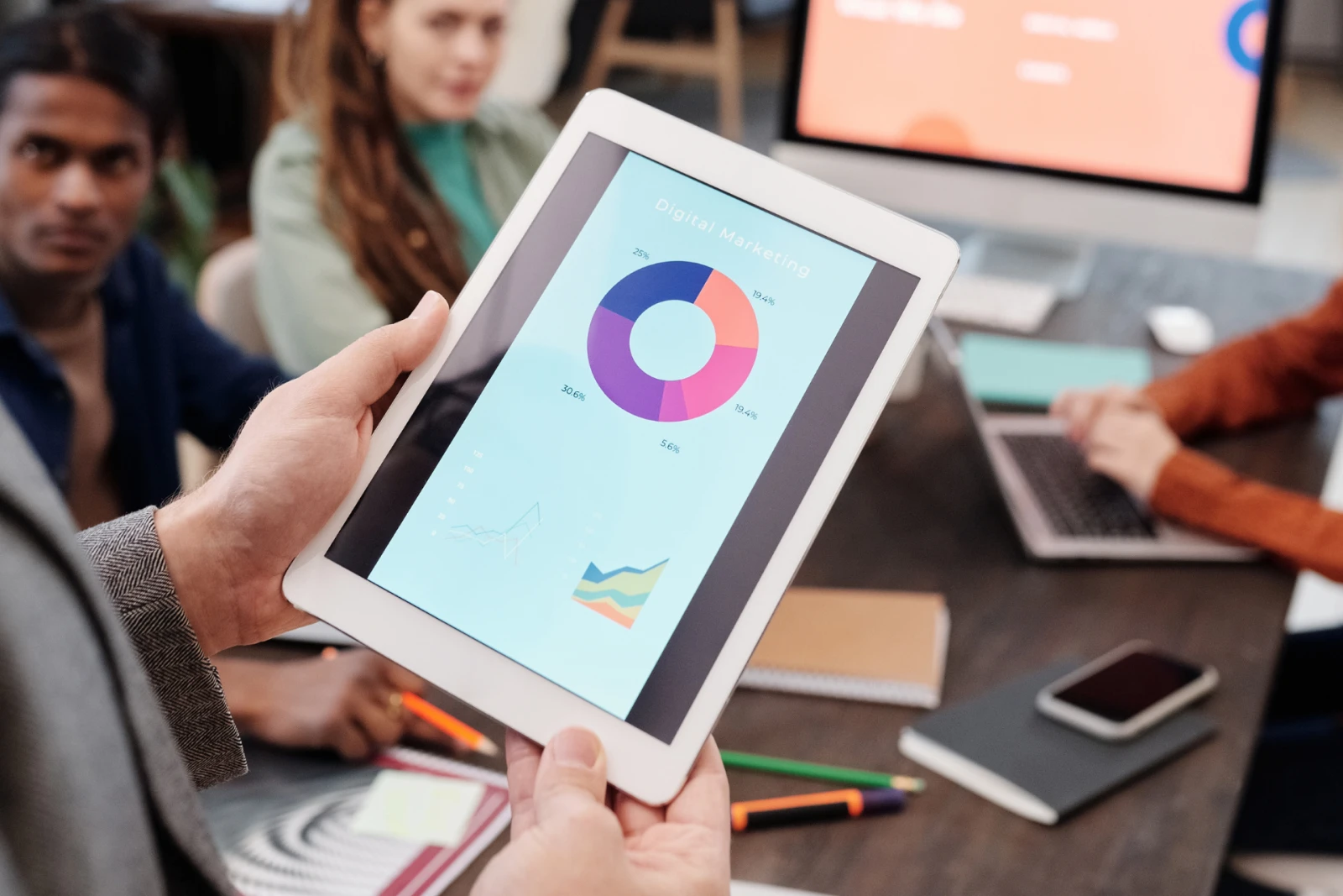 A person holding a tablet with digital marketing pie chart on screen