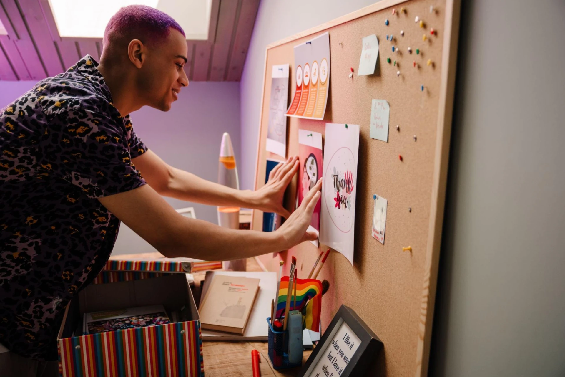 A young man looks at a collage of information on a pinboard.