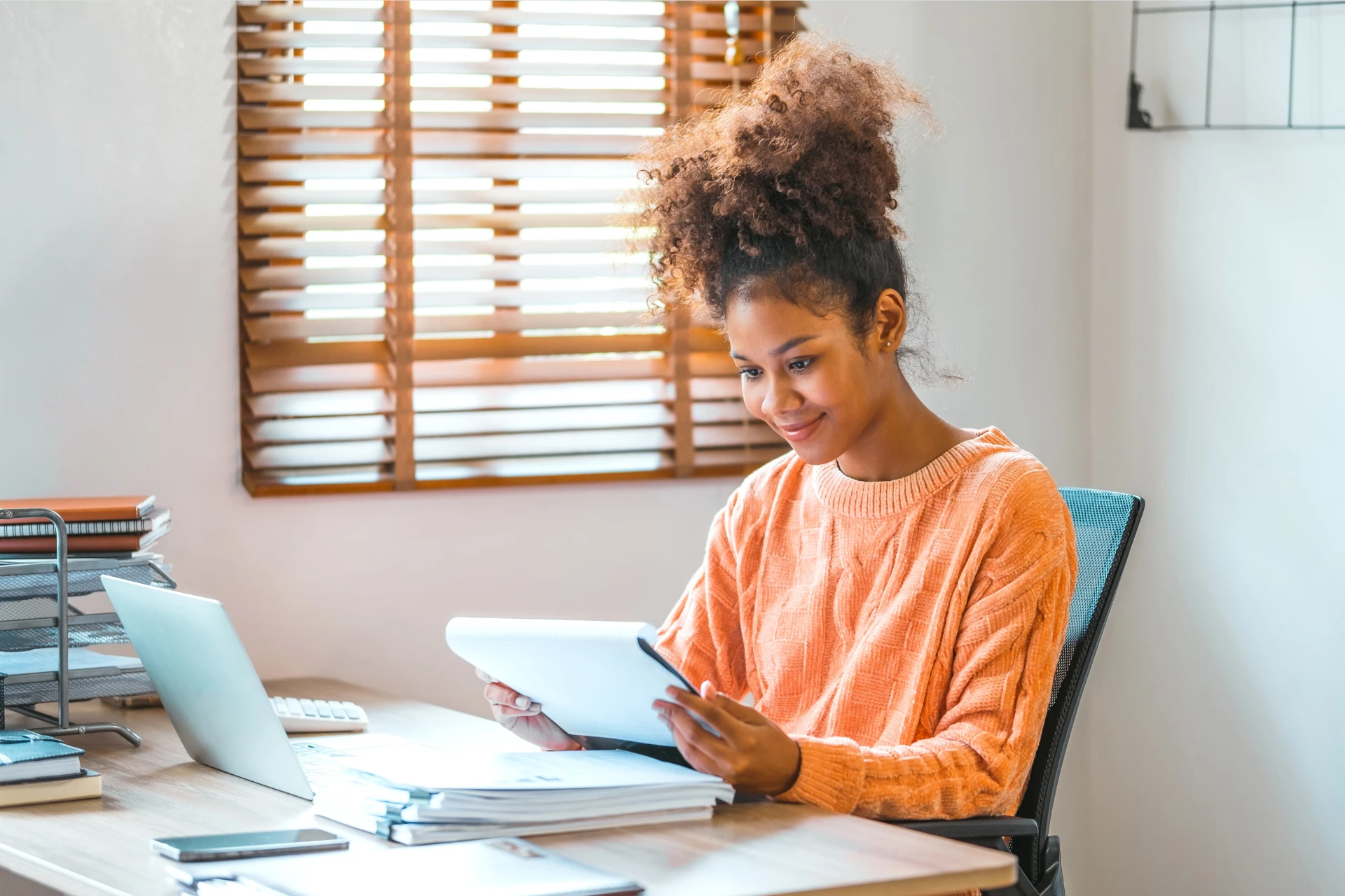 A young woman using a digital tablet and laptop at her desk