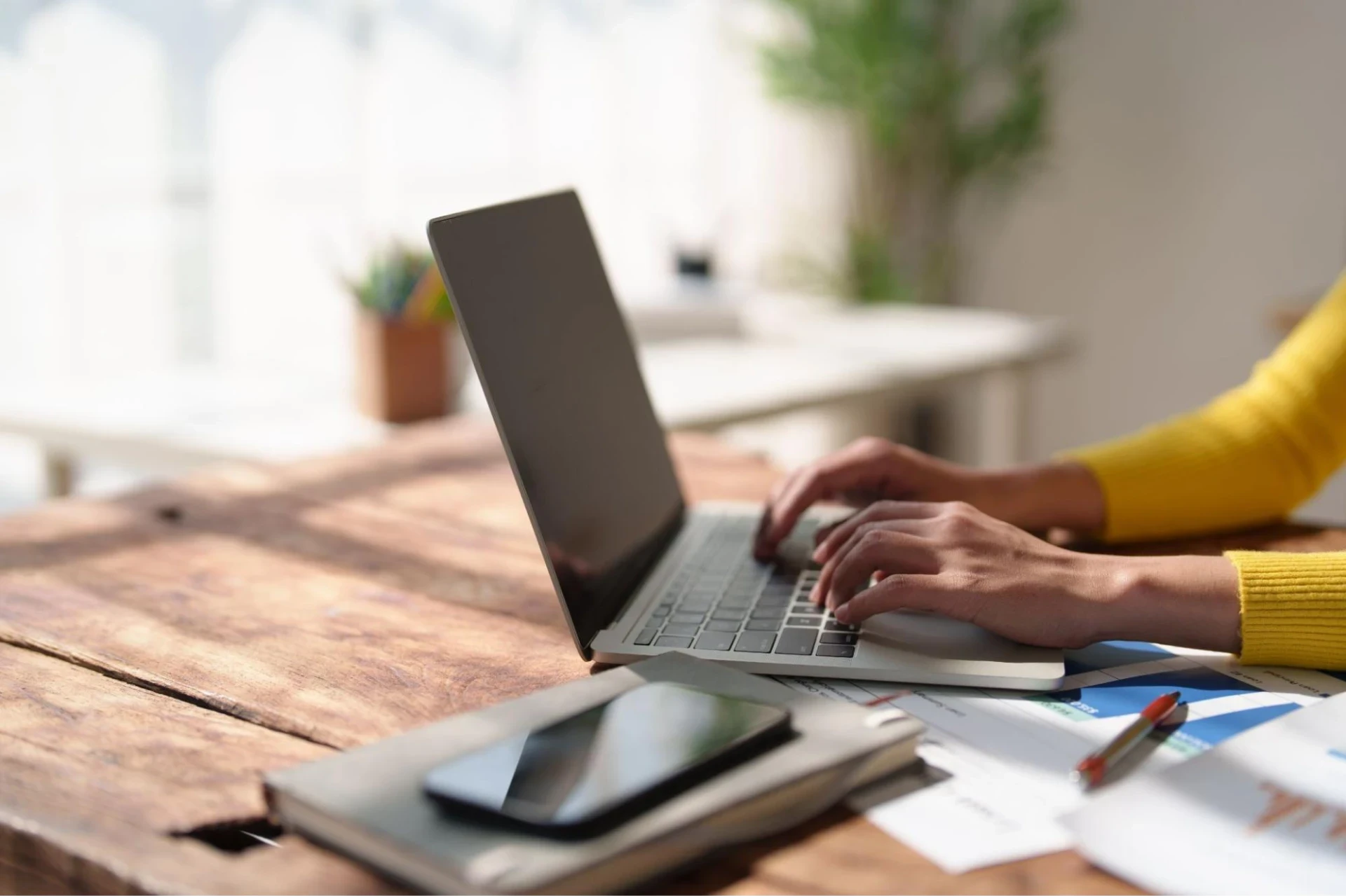 A professional typing on a laptop with documents on the desk, showcasing professional content writing services