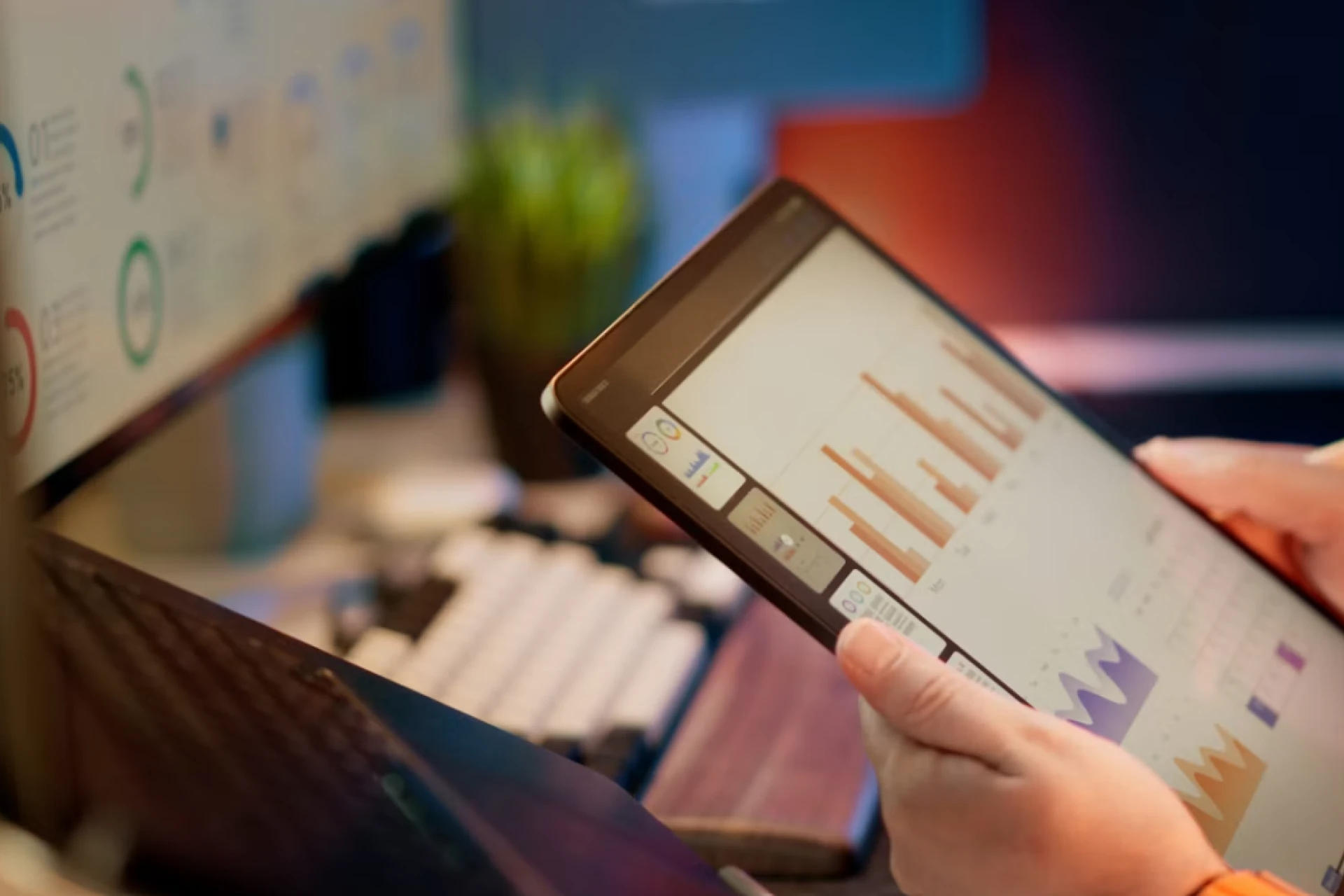 Person reviewing reports from social media management tools on a tablet beside a laptop dashboard.