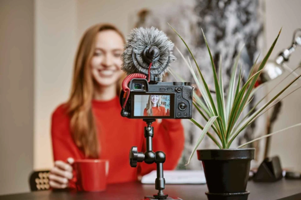 Creator filming branded UGC content with a camera and mic setup at her desk.