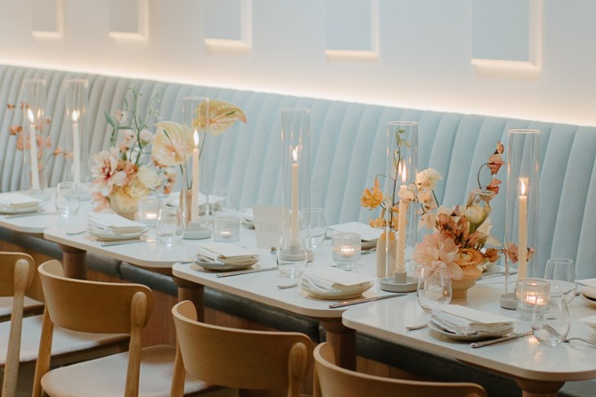 Long banquette dining table set with candles and flowers at Sara in Toronto