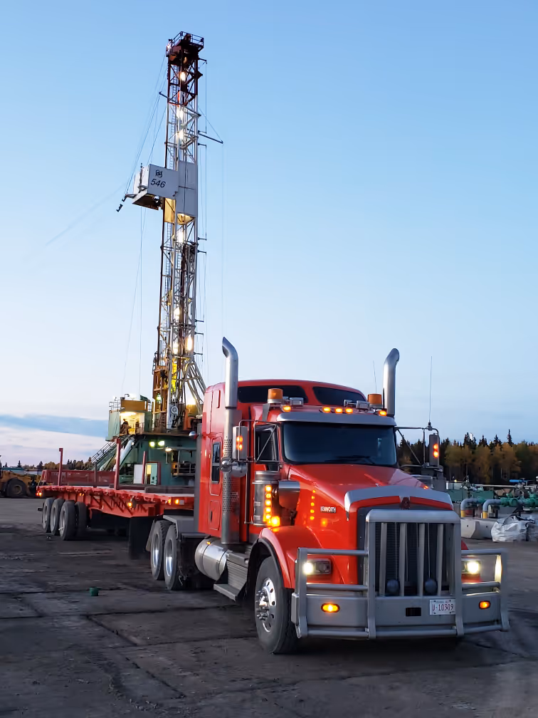 A large red truck parked next to a drilling rig
