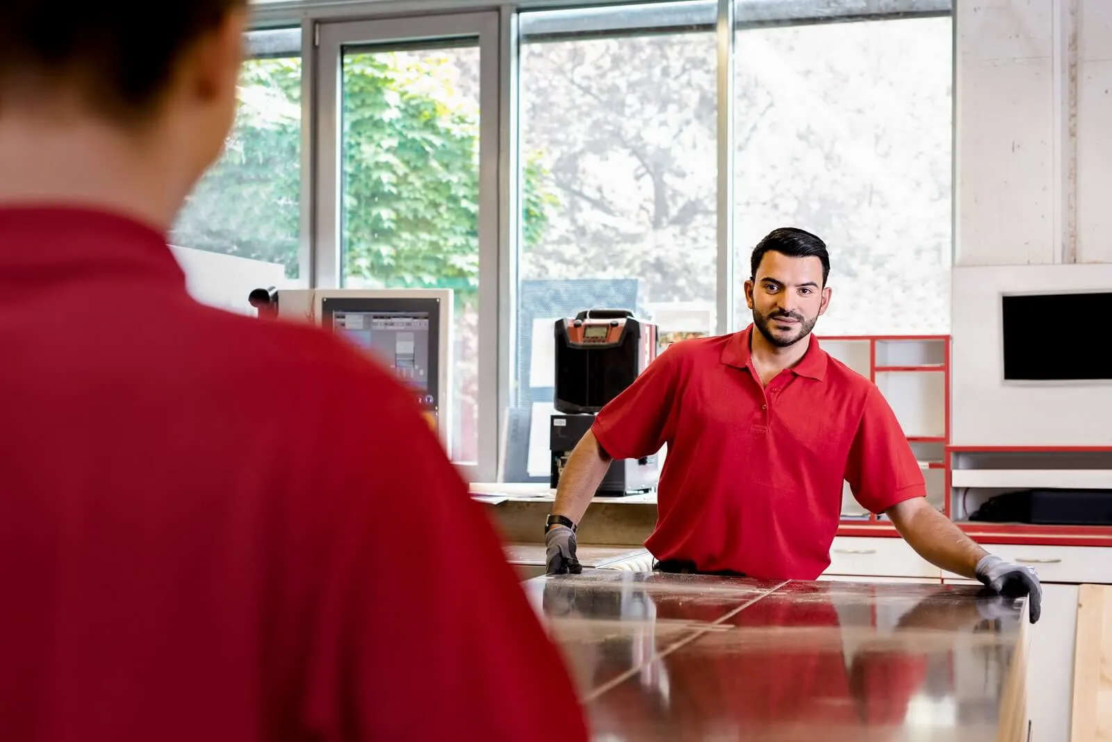 Mitarbeiter in rotem dib-Polo-Shirt in modernem Büro der Integrativen Betriebe Österreich