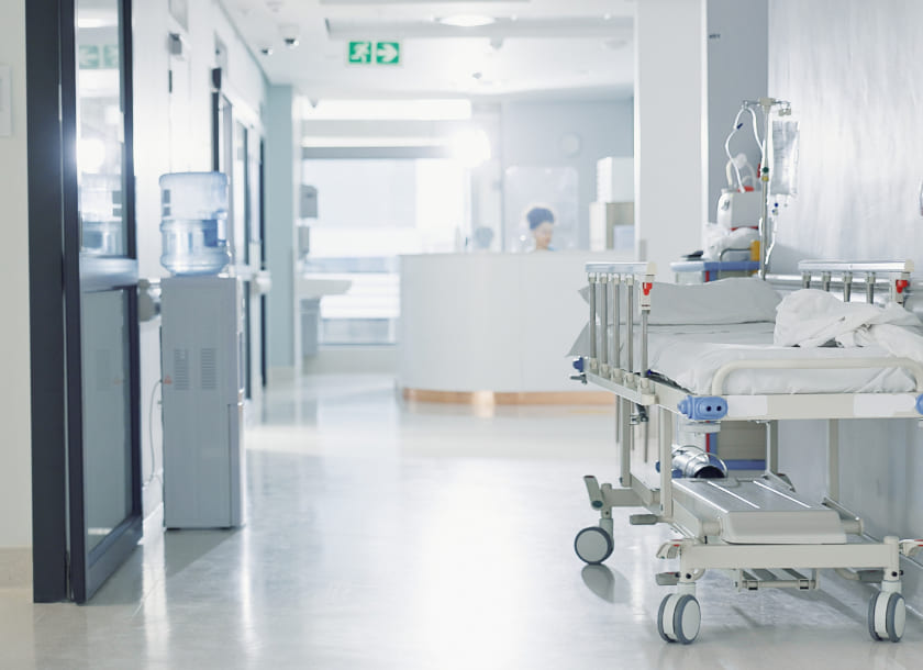 corredor de hospital com maca vazia e recepção ao fundo