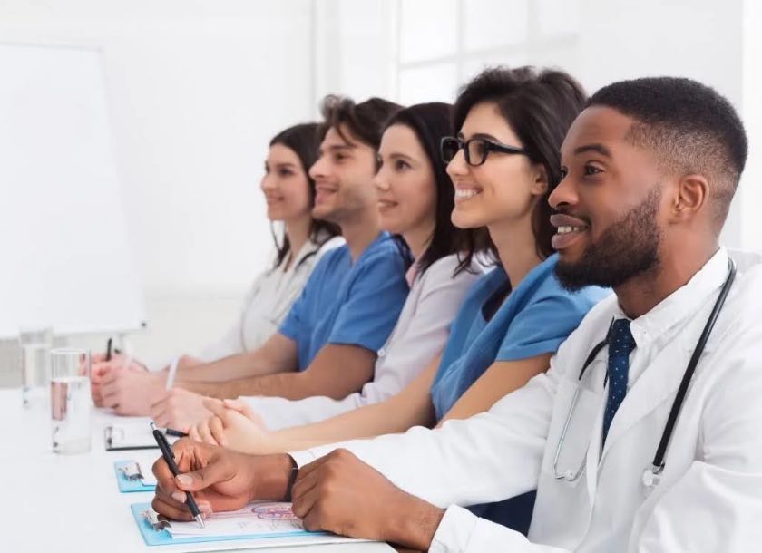 Equipe médica diversa em aula com pranchetas e canetas