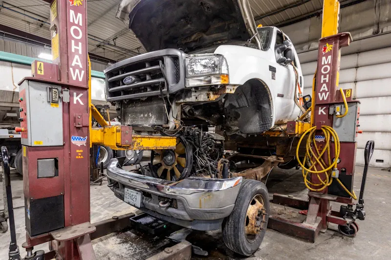 Truck repair on a heavy-duty Ford truck lifted in service bay with front-end components removed. MOHAWK.
