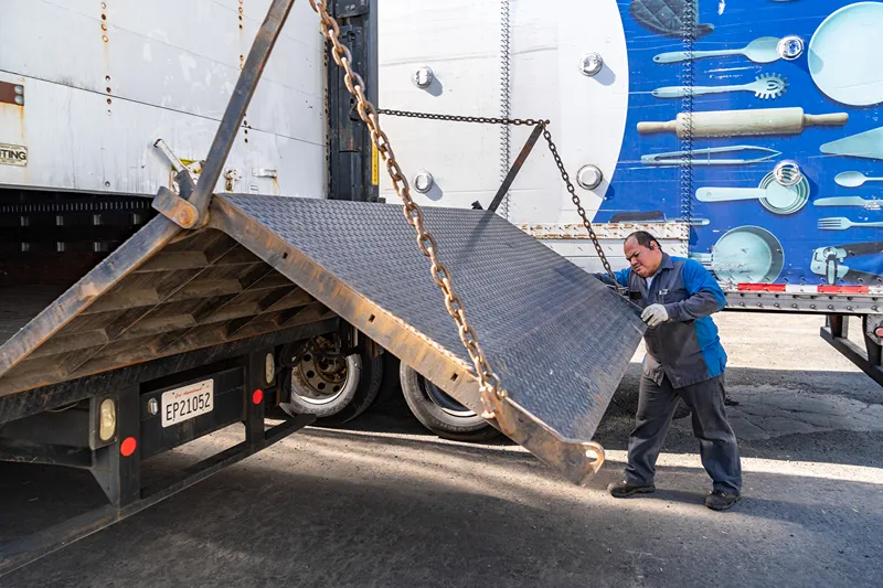 Liftgate service on a heavy-duty truck as a technician inspects the raised steel platform and chains.