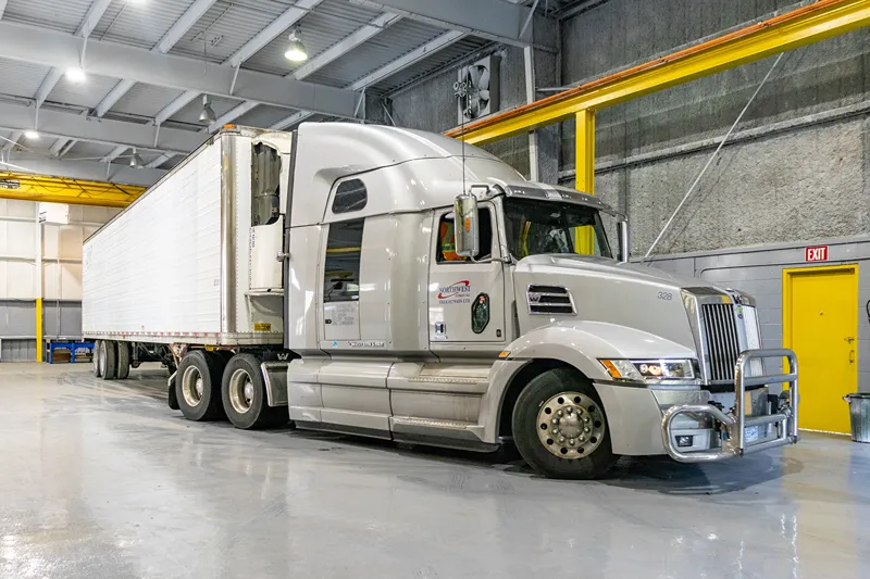 White semi-truck in a heavy-duty repair shop for ICBC repairs, with Northwest Freightways Ltd. branding.