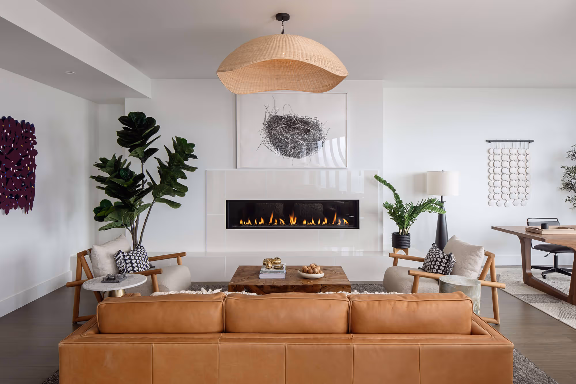 Premium Residence living room with tan leather sofa, two wooden armchairs with cushions, a wooden coffee table, and a long fireplace set into the wall.
