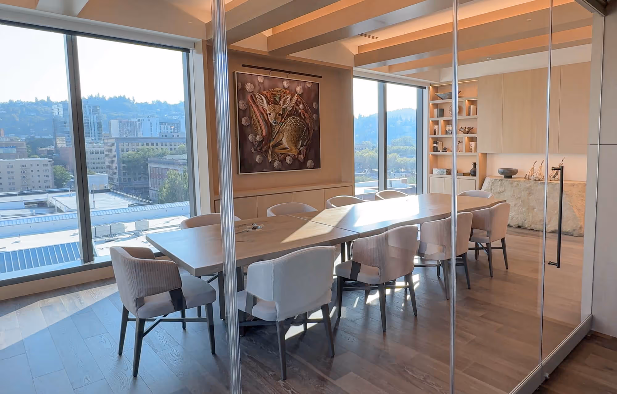 Executive Boardroom in the Exclusive Owners' Lounge with large windows, a long wooden table, upholstered chairs, and nature-themed artwork on the wall.