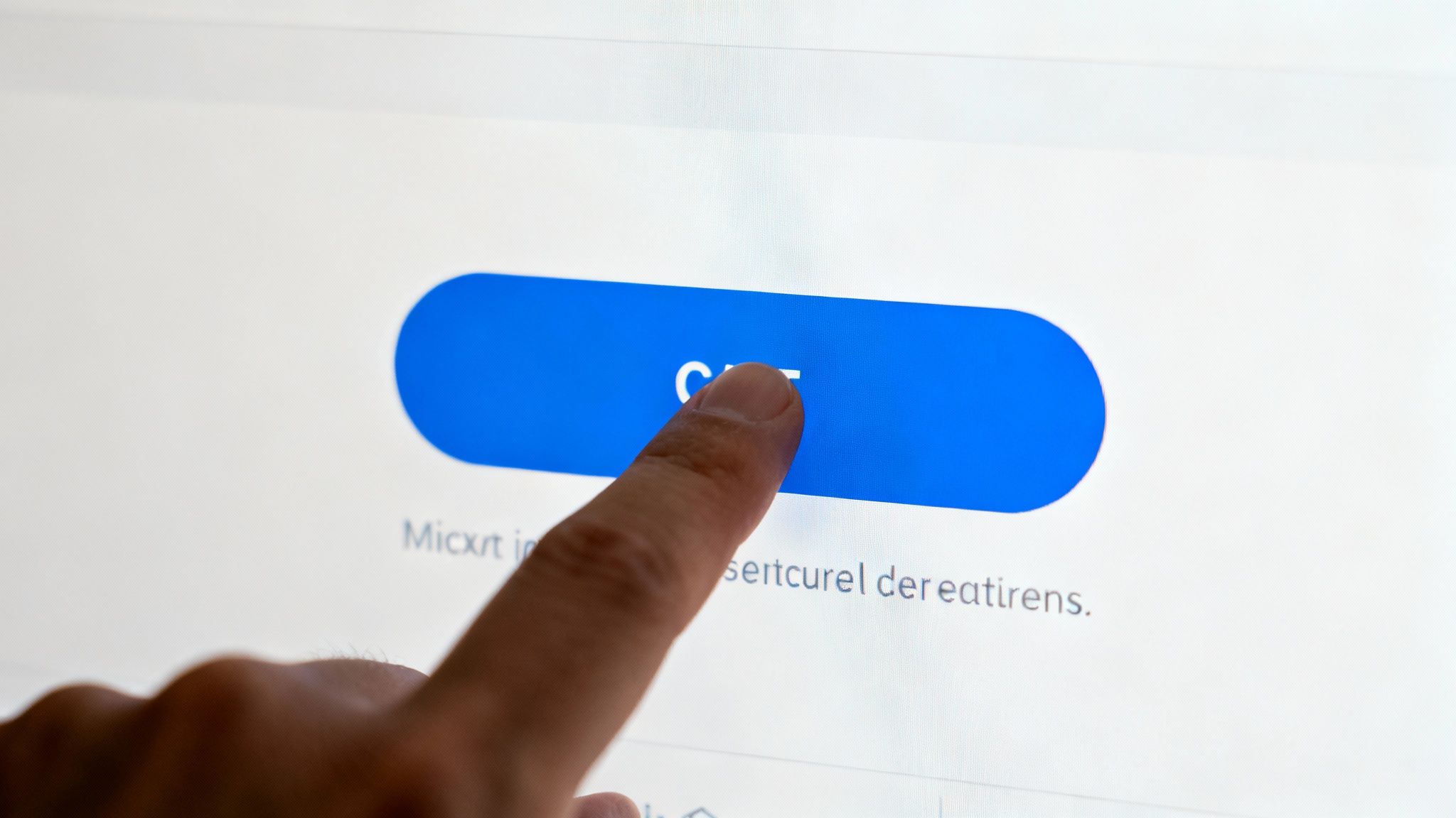 Close-up of a finger tapping a blue button with white text on a digital screen.