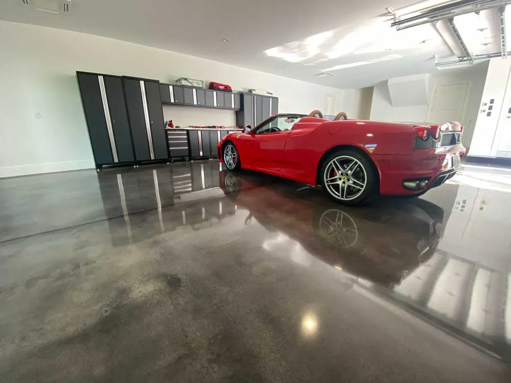 Garage with grey epoxy floor and red car parked.