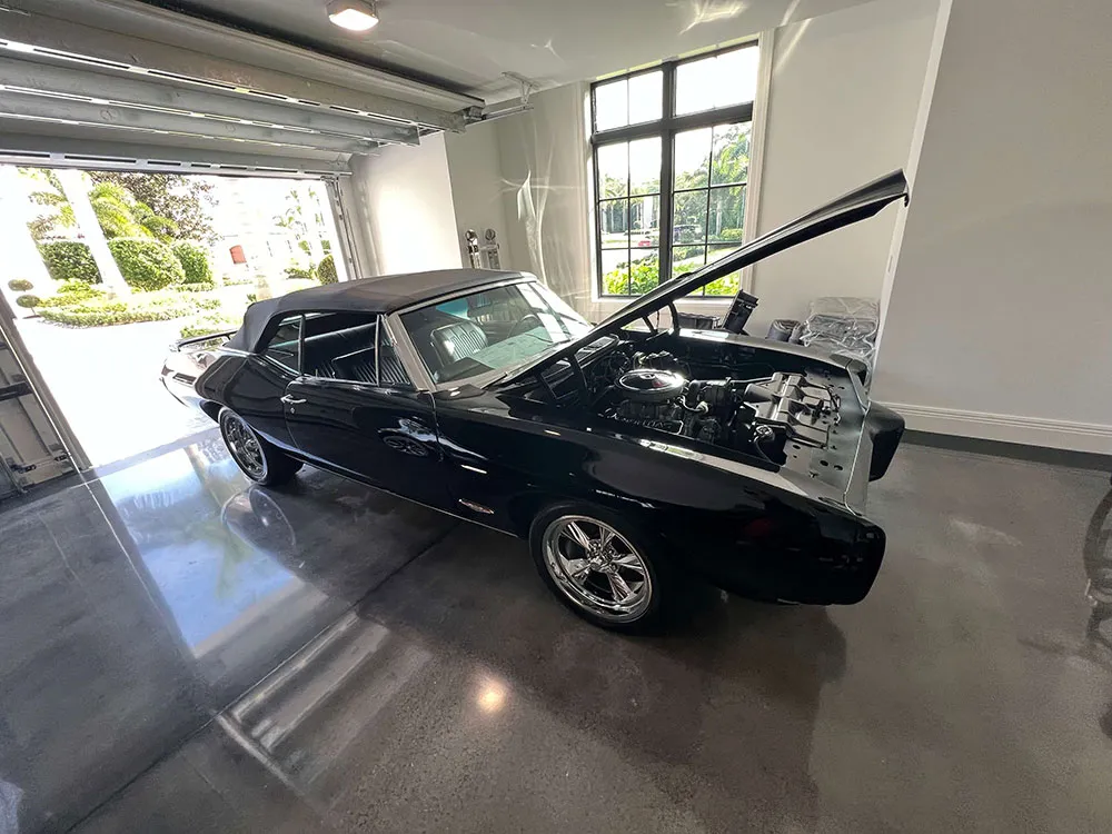 Garage with grey epoxy floor and a black car parked inside.