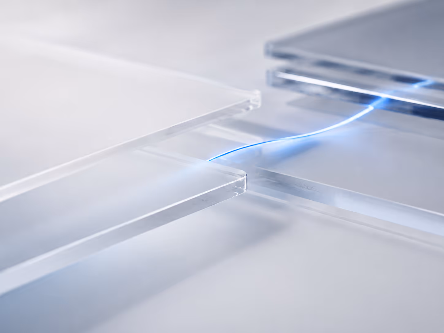 A thin blue light beam connecting two clear glass slabs on a white surface.