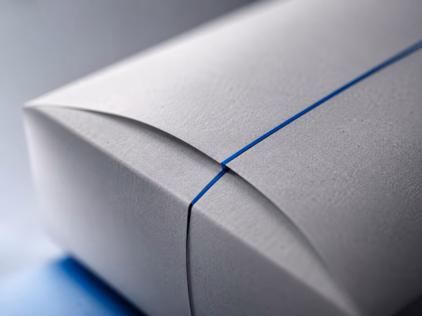 Close-up of a gray box with a precise blue line running along its folded edges.