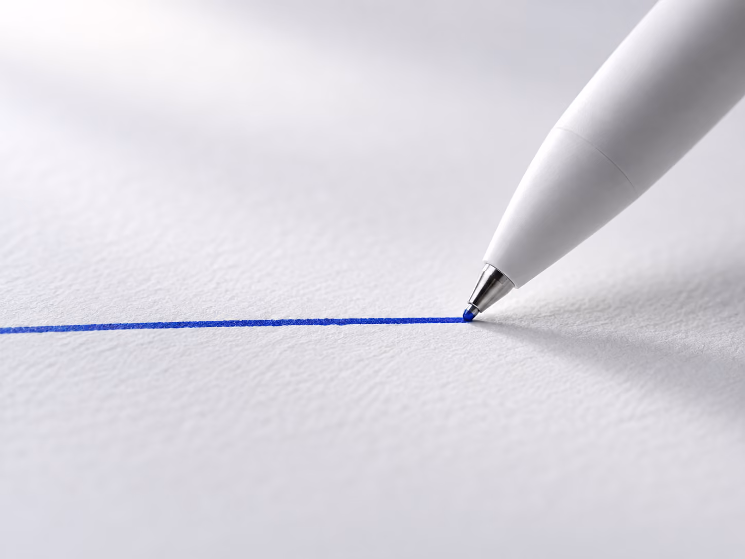 A white pen resting at the end of a blue line drawn on paper