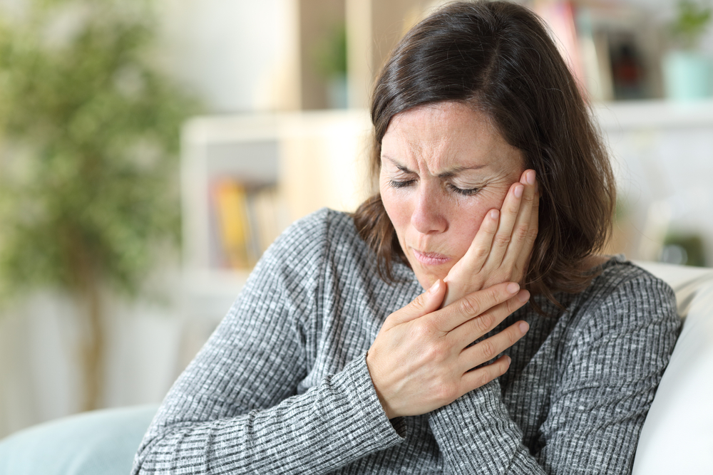 Woman holding her jaw in discomfort from TMJ