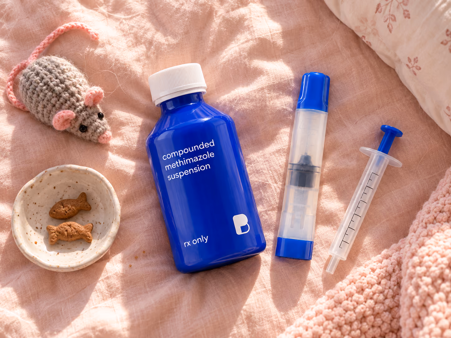 Flatlay of compounded methimazole suspension, ear gel applicator and oral syringe on blush linen, prepared by Bayview Pharmacy