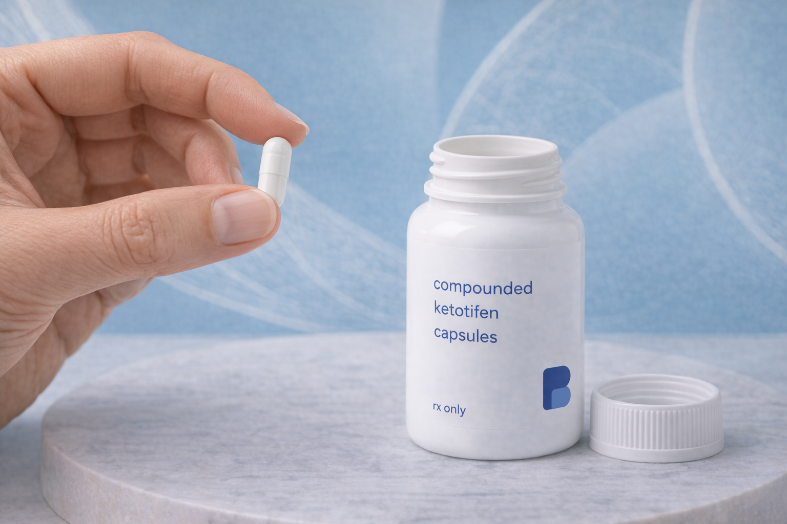 Hand holding a ketotifen capsule beside an open pharmacy bottle
