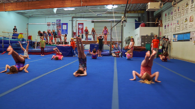 A group of gymnasts doing a back roll in sync with each other.