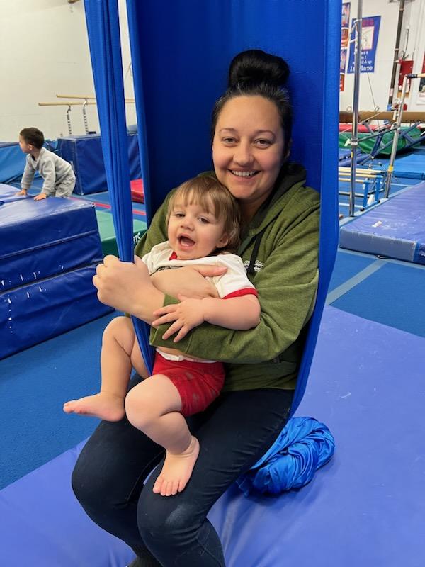 A mom and her toddler sitting in an aerial sling.