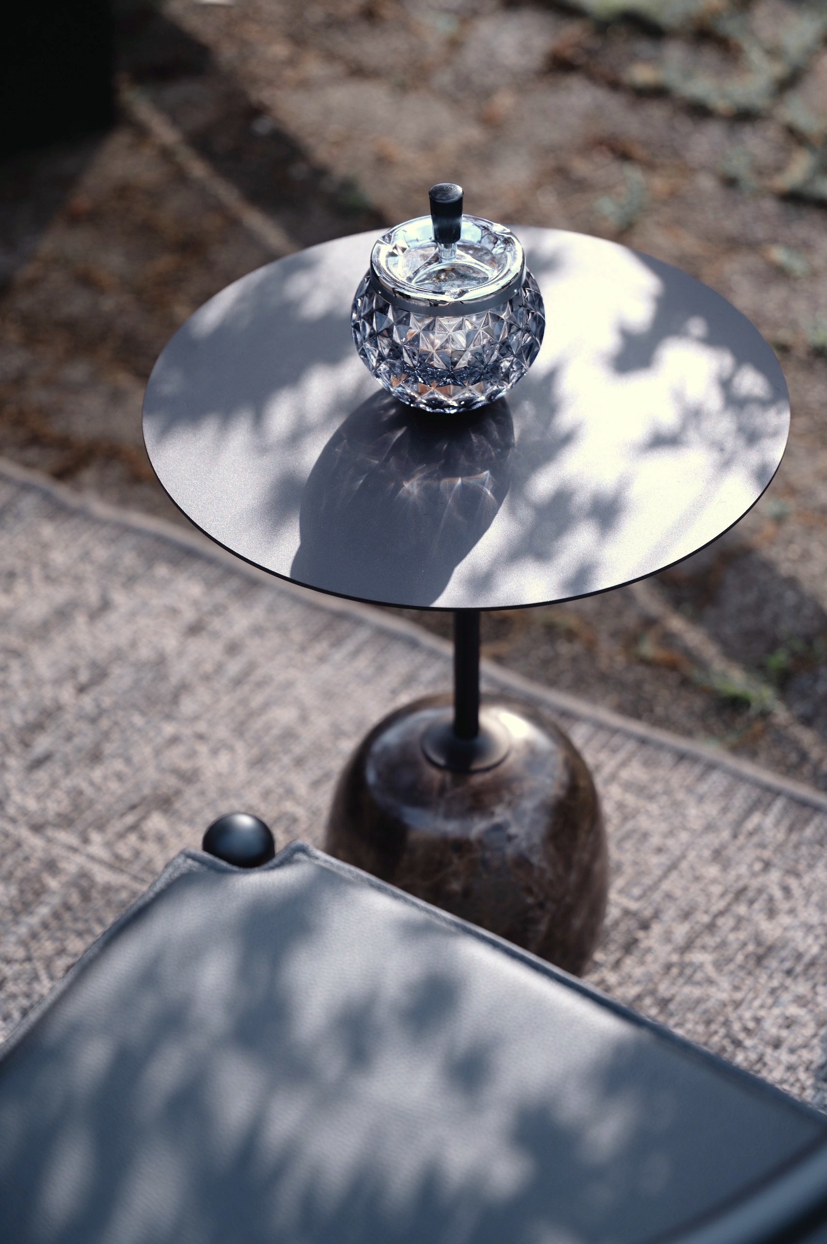 Modern marble side table with a metal top paired with a black wishbone chair and leather seat.