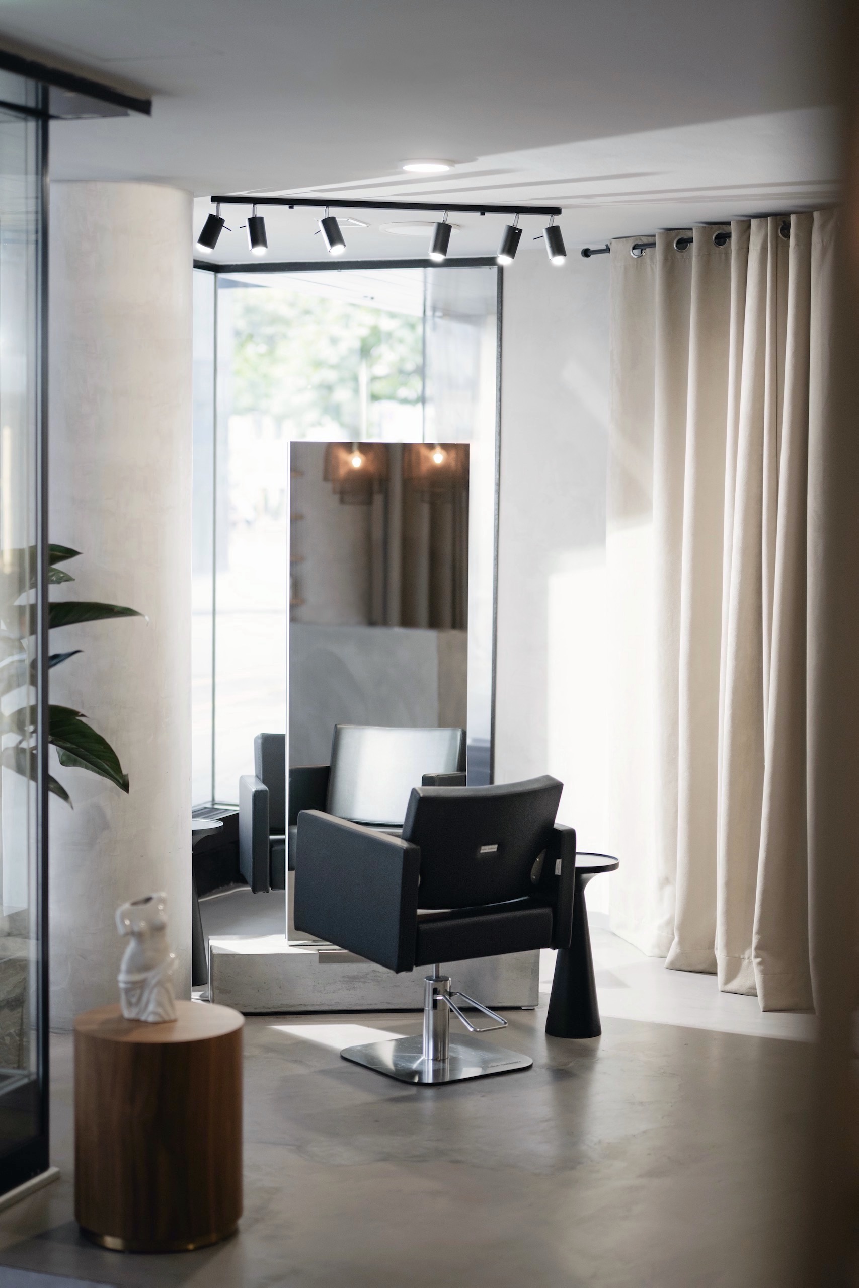 Hairdresser's chair on concrete floor in front of a big mirror.