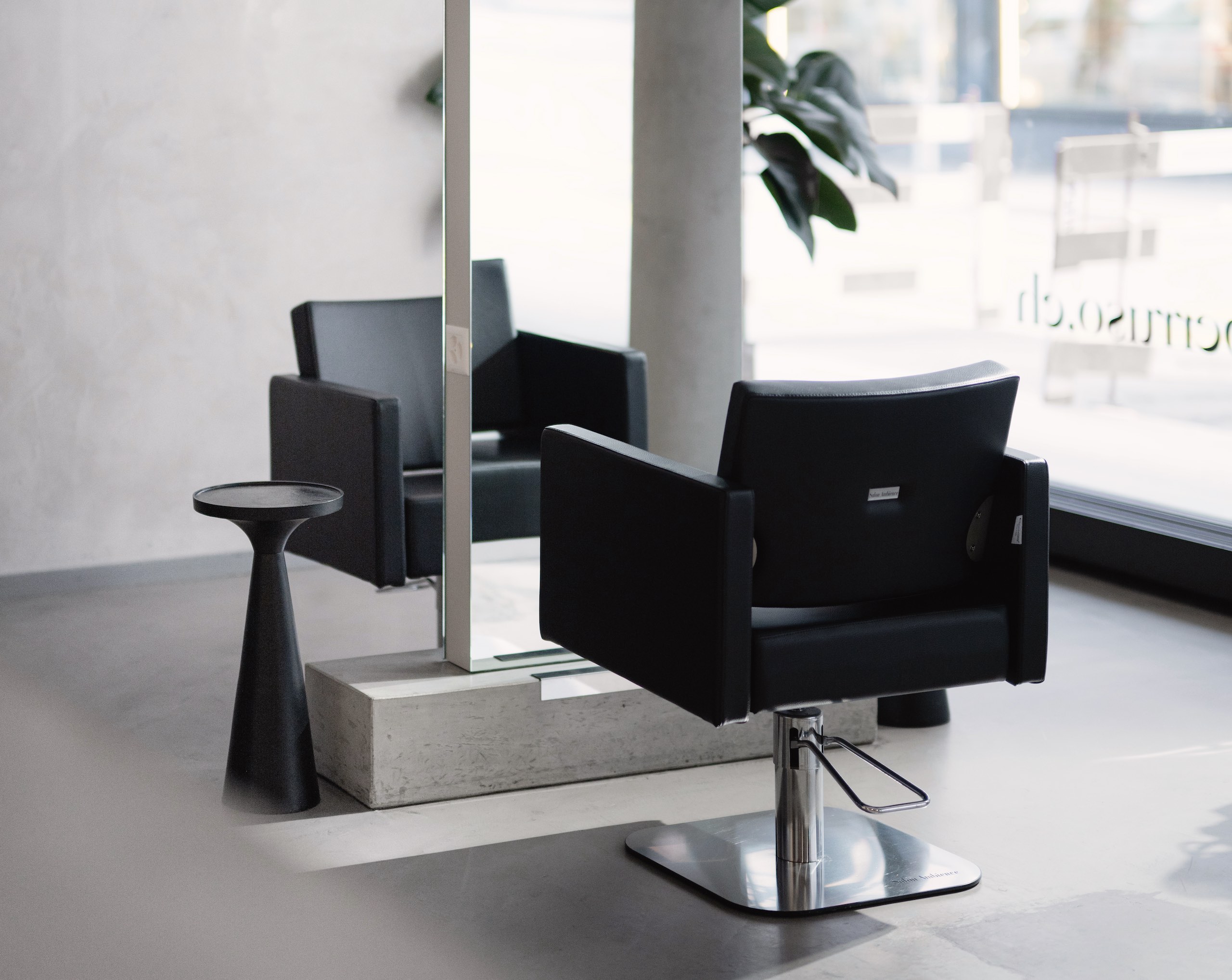 Hair salon with two chairs divided by tall mirror.
