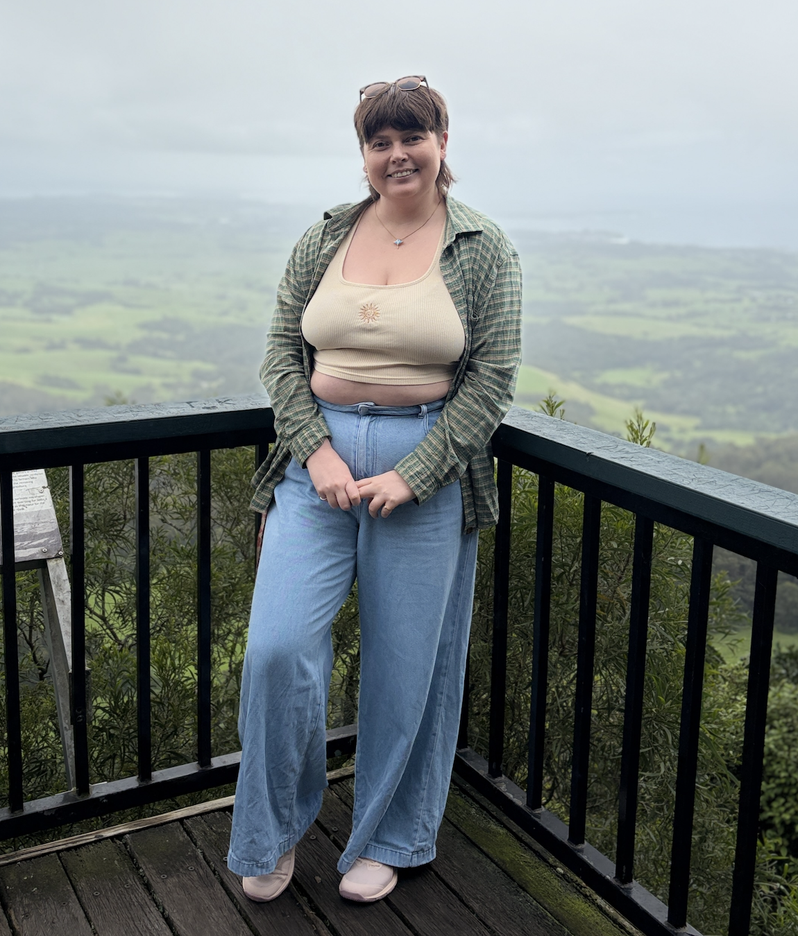 Smiling person with short blonde hair wearing a two-tone pink and blue shirt with heart-shaped buttons.