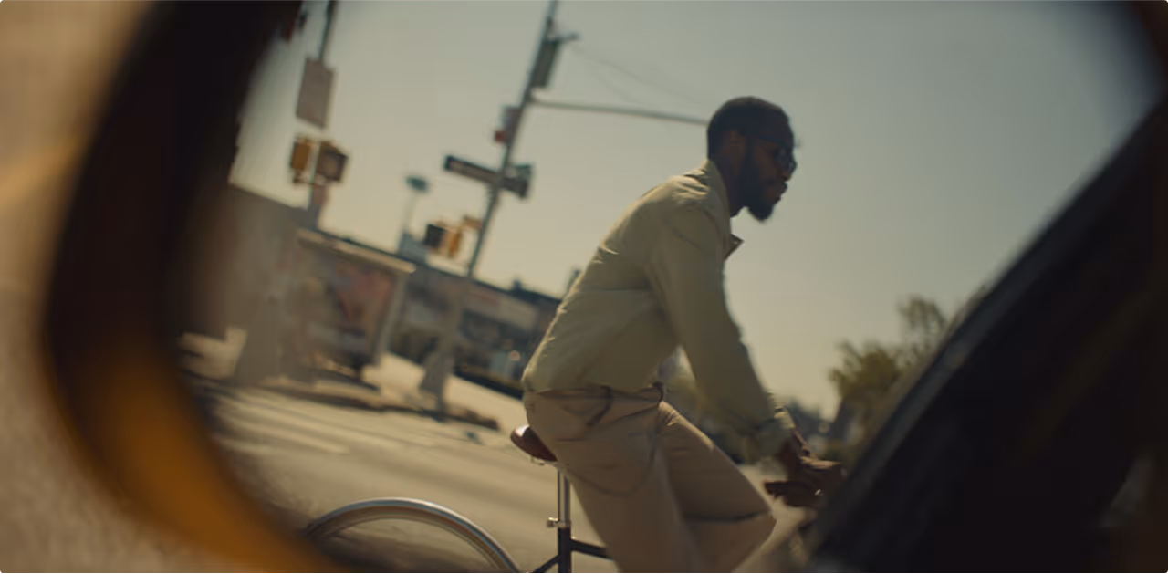 a black man wearing sunglasses and riding a bike in the city