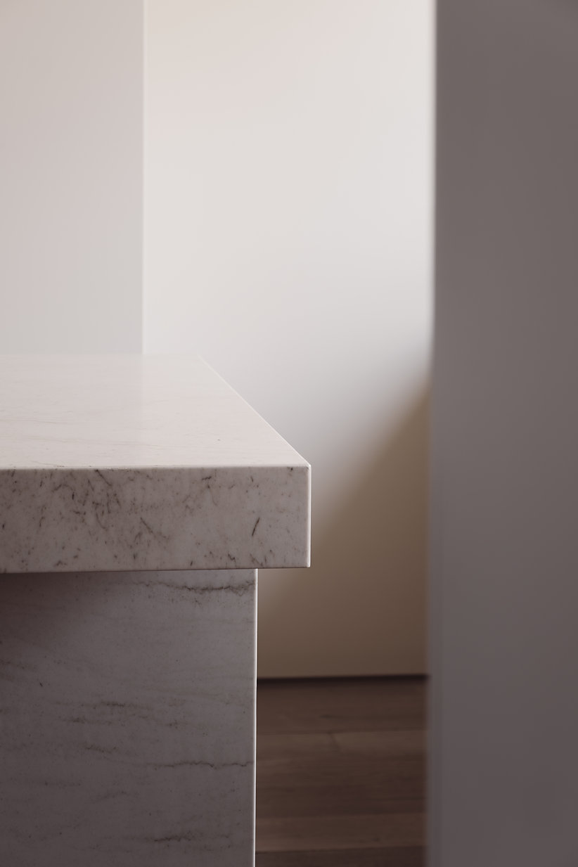 Close-up of a polished marble countertop edge with subtle veins and soft natural lighting.