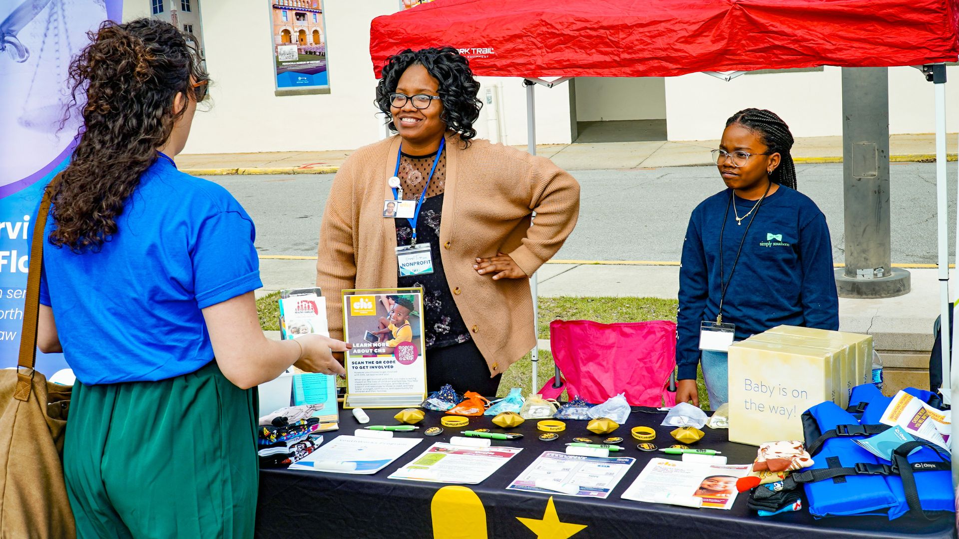 A photo of a woman talking with another woman at a booth.