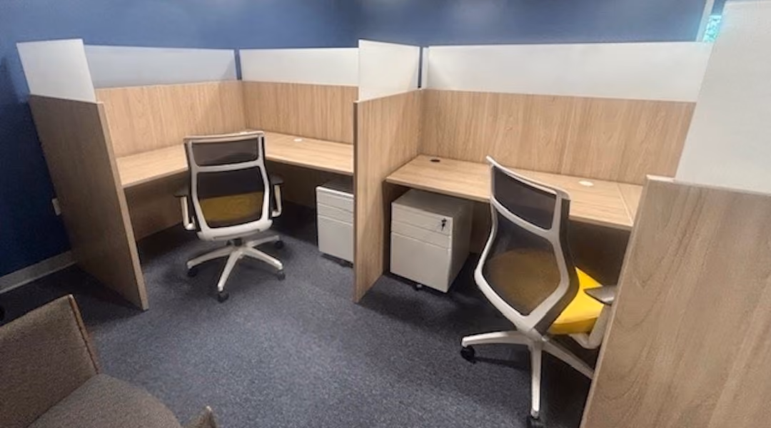 Two adjacent wood-paneled office cubicles with ergonomic chairs and natural lighting