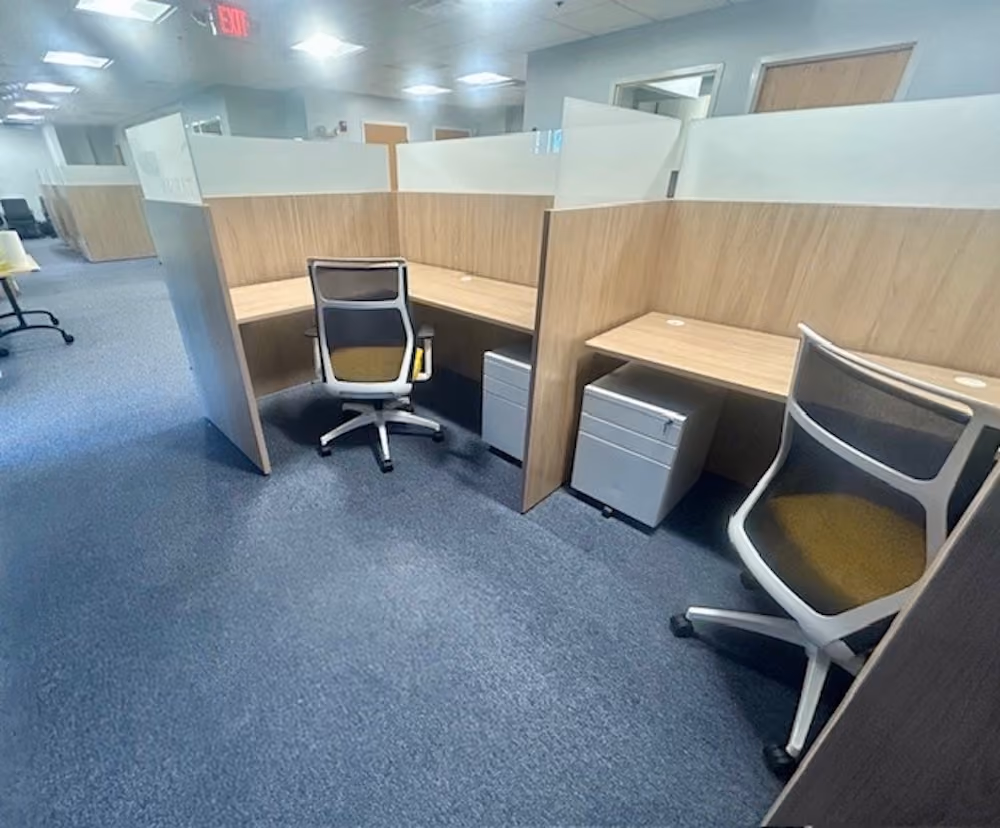 Open-plan office cubicles with wood dividers, ergonomic chairs, and drawer storage