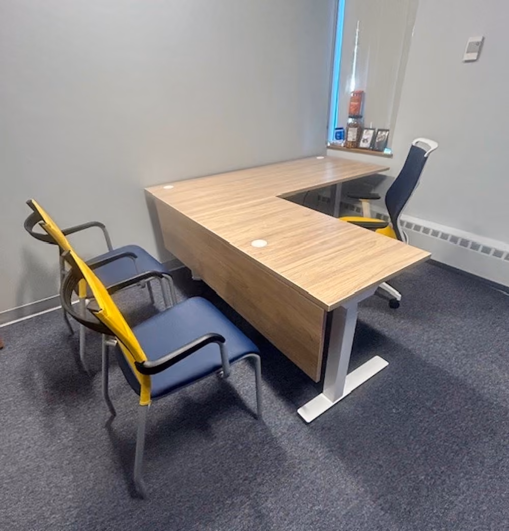 Executive corner desk setup with guest seating and personal workspace in private office