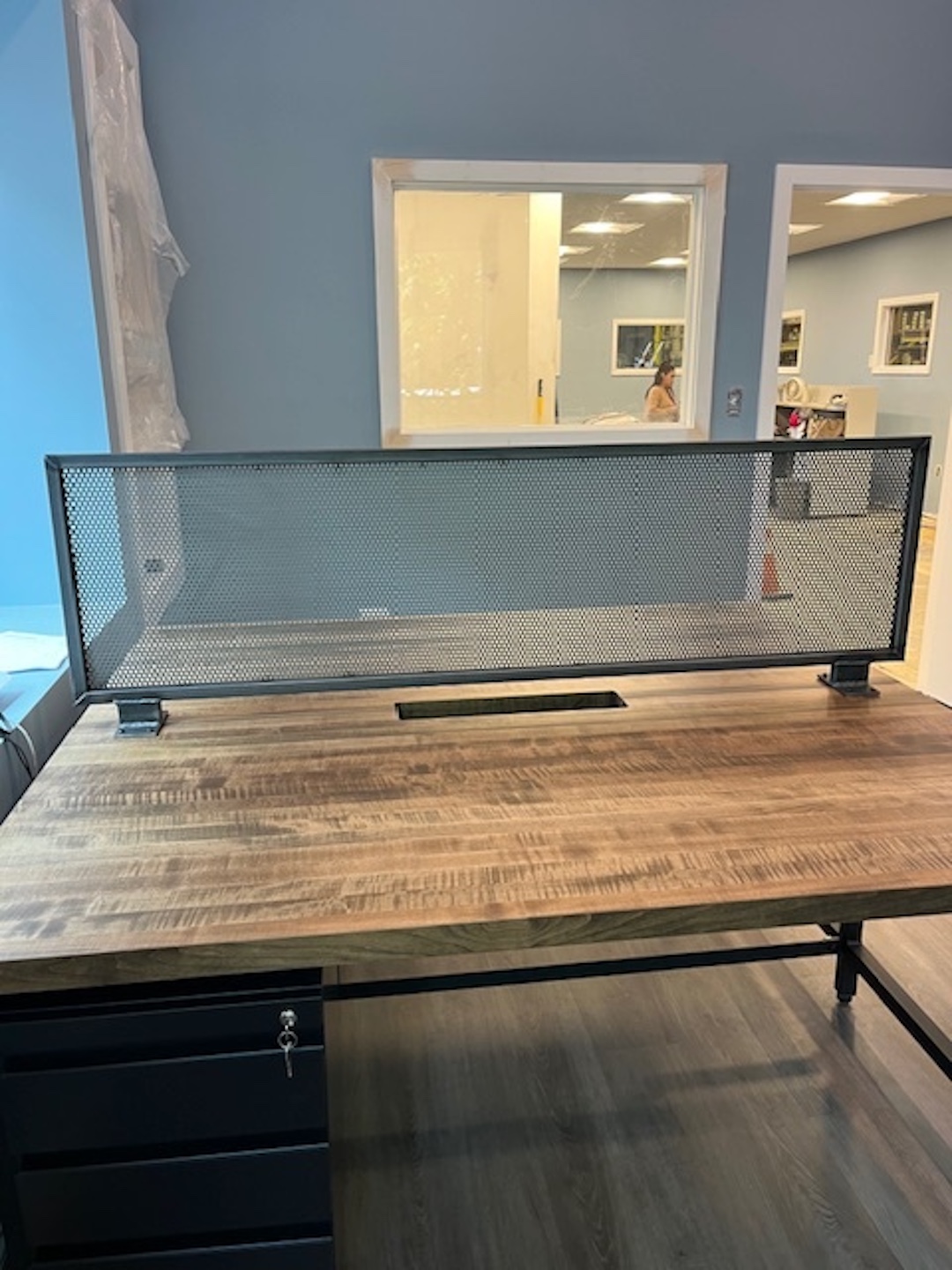 Close-up view of round wood cafe table with two guest chairs in modern office space with laminate wood flooring and blue wall