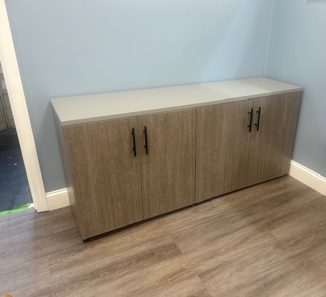 Row of contemporary office cubicles with frosted glass partitions and wood-tone finishes in a commercial workspace.