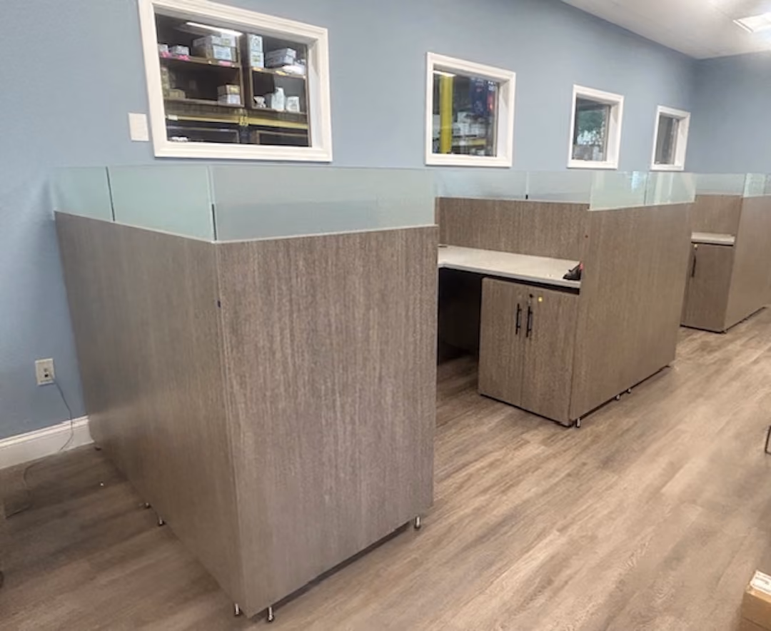 Contemporary wood storage credenza with black handles against a blue wall in a modern office setting.