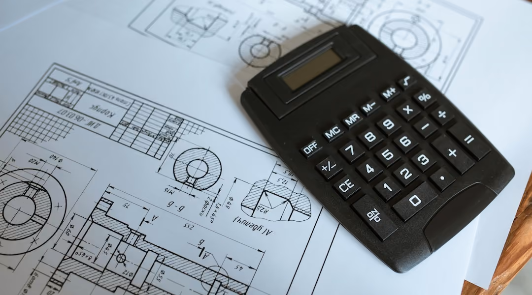 Blueprint plans for and office on a desk with a calculator.