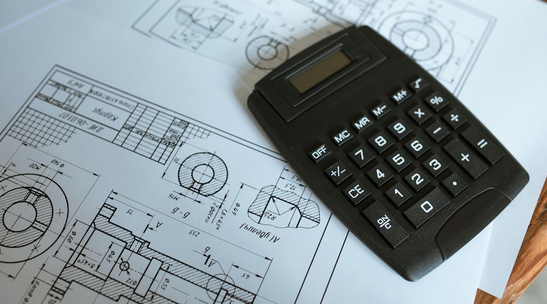 Blueprint plans for and office on a desk with a calculator.