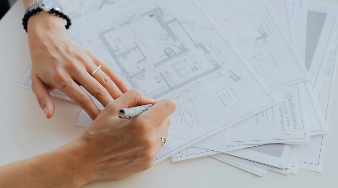 Achitect drawing on a floor plan to assign furniture to a space designed by Office Gallery.