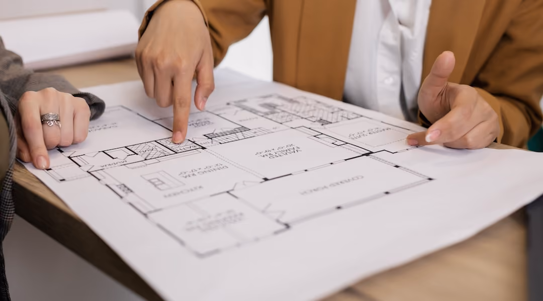 Two professionals reviewing architectural plans, focused on floor layout and design details.