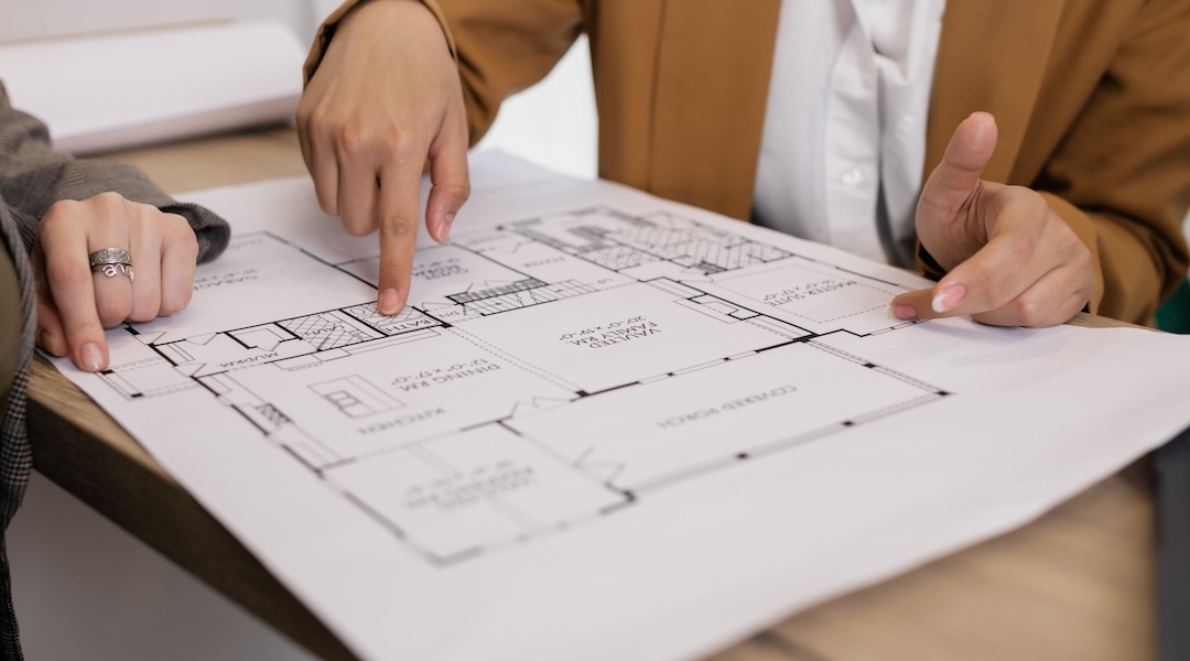 Two professionals reviewing architectural plans, focused on floor layout and design details.