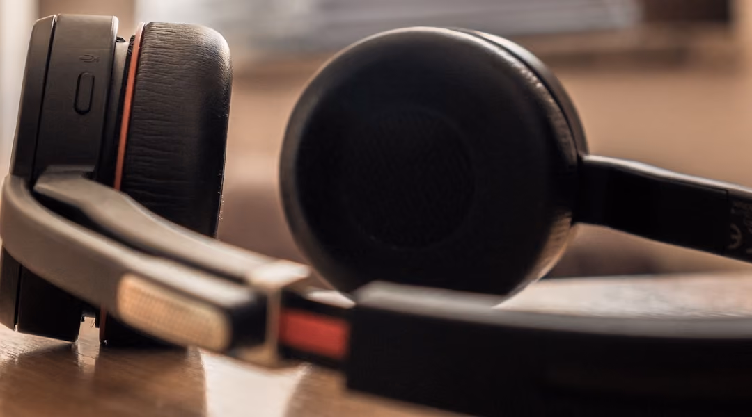 A close-up shot of black headphones on a wooden surface with soft background lighting.